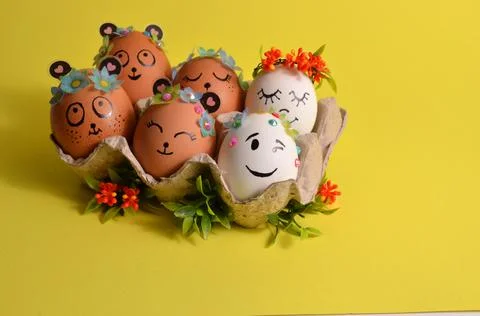 Easter eggs with cute faces and flowers in an egg container. Spring. Easter. Stock Photos