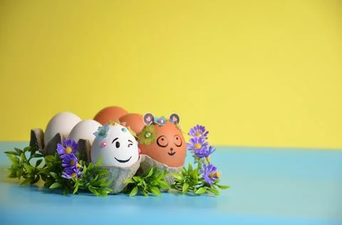Easter eggs with cute faces and flowers on a yellow-blue background. Easter. Foto stock