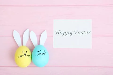 Easter eggs with cute faces and ears on a colored background. Stock Photos