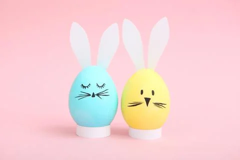 Easter eggs with cute faces and ears on a colored background. Photos