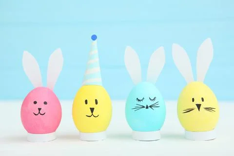 Easter eggs with cute faces and ears on a colored background. Stock Photos