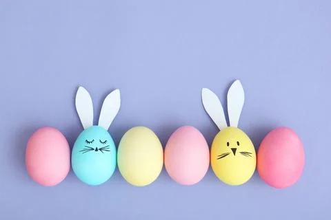 Easter eggs with cute faces and ears on a colored background. Stock-Fotos