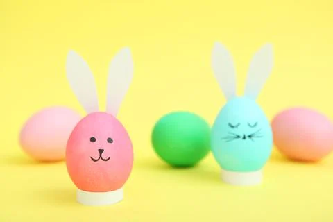 Easter eggs with cute faces and ears on a colored background. Stock-Fotos