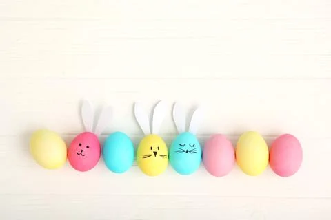 Easter eggs with cute faces and ears on a colored background. Stock Photos