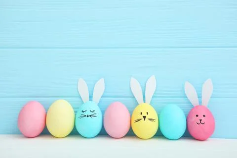Easter eggs with cute faces and ears on a colored background. Stock Photos