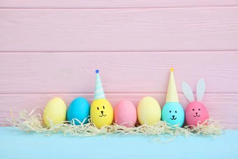 Easter eggs with cute faces and ears on a colored background. Stock Photos