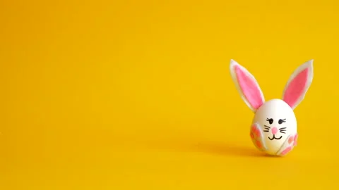 Easter eggs decorated like bunnies and chickens fill the yellow background Stock Footage 149819207