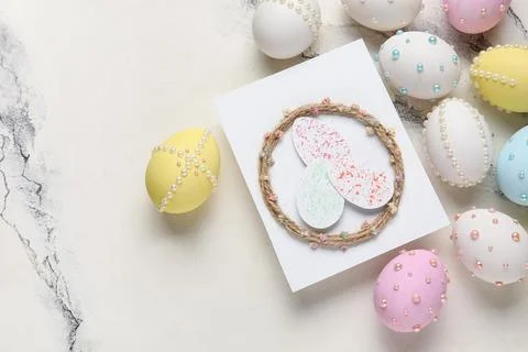 Easter eggs decorated with pearls and greeting card on marble background Stock Photos
