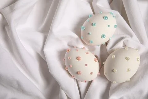 Easter eggs decorated with pearls on white fabric Stock Photos
