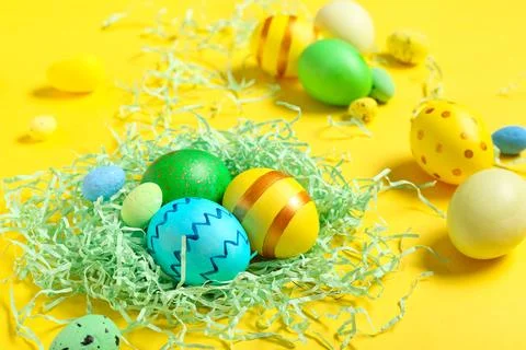 Easter eggs with decorative shredded paper on yellow background Stock Photos