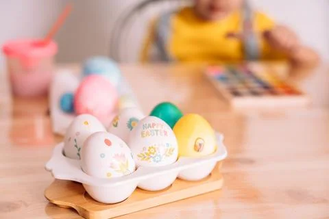 Easter eggs of different colors and in stickers in a white tray on a wooden Stock Photos