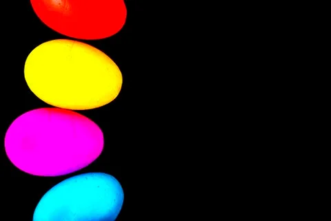 Easter eggs of different colors on a black background. Stock Photos