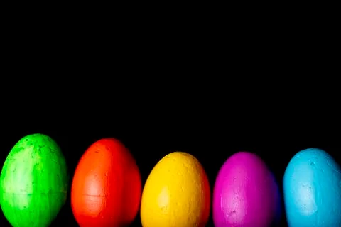 Easter eggs of different colors on a black background. Stock Photos