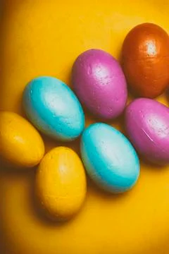 Easter eggs of different colors on a yellow background. Stock Photos