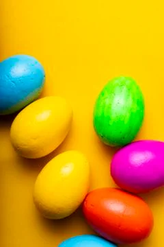 Easter eggs of different colors on a yellow background. Stock Photos