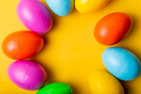 Easter eggs of different colors on a yellow background. Stock Photos