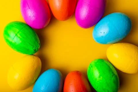 Easter eggs of different colors on a yellow background. Stock Photos