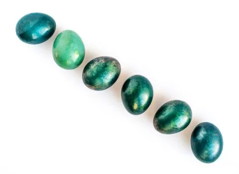 Easter eggs in different shades of turquoise and gold in a diagonal row on wh Stock Photos