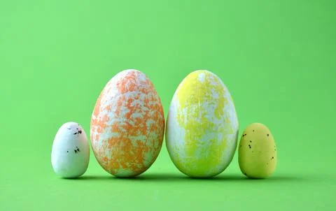 Easter eggs of different sizes. Green background. Stock Photos