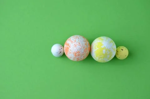 Easter eggs of different sizes. View from above. Green background. Stock Photos