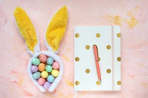 Easter eggs, ears, notebook and pen on workspace Stock Photos