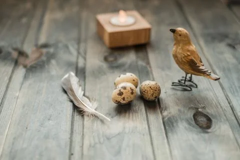 Easter eggs, feather, candle and a bird on wooden background with a space f.. Stock Photos