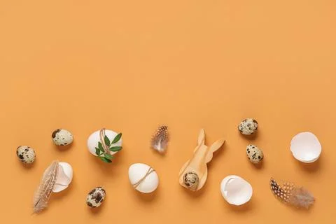 Easter eggs with feathers and leaves on orange background Stock Photos