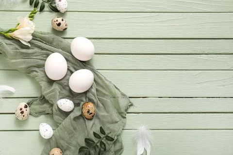 Easter eggs with feathers, leaves and beautiful flower on green wooden backgr Stock Photos
