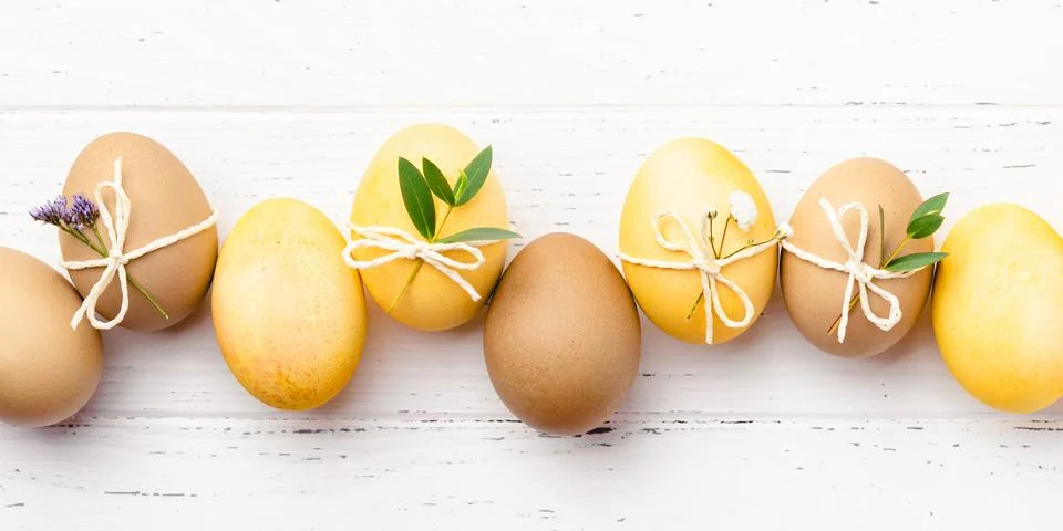 Easter eggs with flowers on a white table. Stock Photos