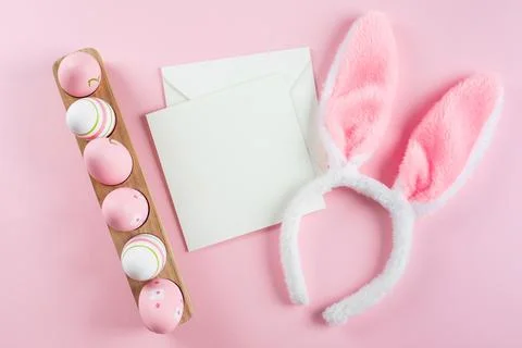 Easter eggs, fluffy bunny ears, white empty card for congratulations. Mocku.. Stock Photos