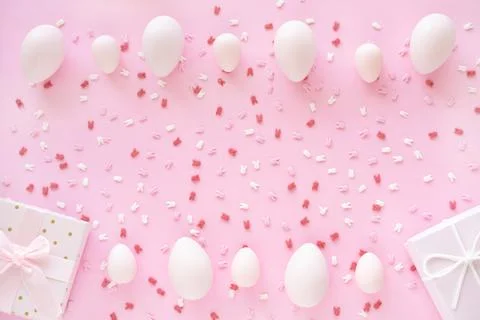 Easter eggs frame with bunny ears sugar sprinkle and gift box on pink background Stock Photos