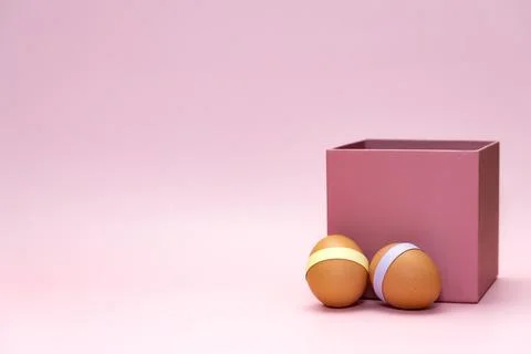 Easter eggs in front of pink square box on empty background Stock Photos