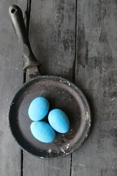 Easter eggs in a frying pan on rustic wooden background Stock Photos