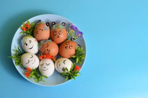 Easter eggs with funny faces on a blue plate. Easter. Stock Photos