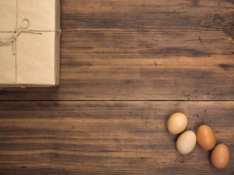 Easter eggs, gift box on old wooden table from planks. Top view with space for Stock Photos