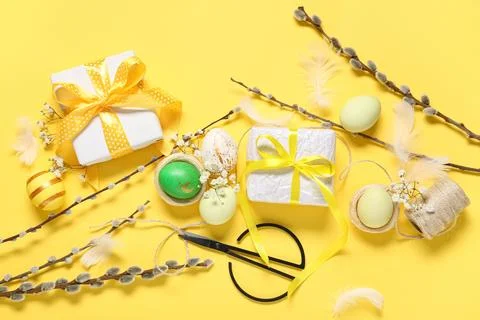 Easter eggs with gift boxes, rope, flowers and pussy willow branches on yello Stock Photos