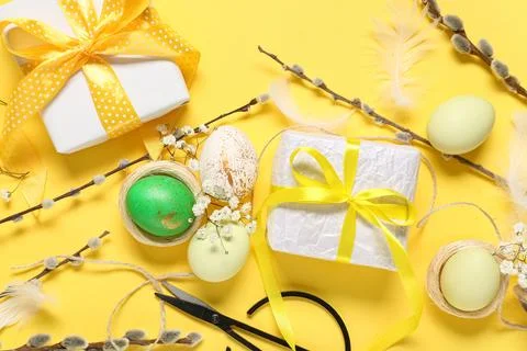 Easter eggs with gift boxes, rope, flowers and pussy willow branches on yello Stock Photos