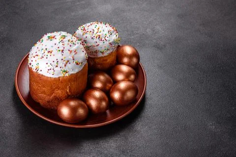 Easter eggs gold and bronze and Easter cake on a dark background Stock Photos