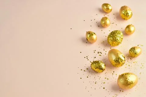 Easter eggs with gold sequins on a beige background. Stock Photos