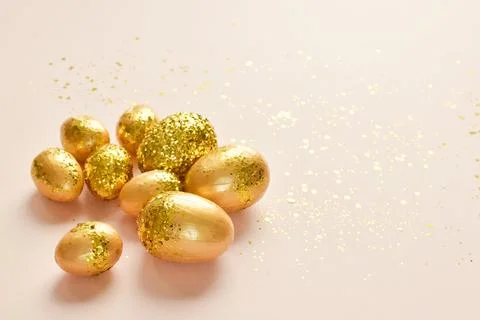 Easter eggs with gold sequins on a beige background. Banner for a happy Easter Stock Photos