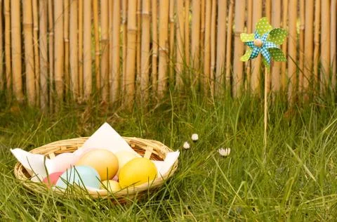Easter eggs in the grass, with windmill and bamboos in the background Stock Photos
