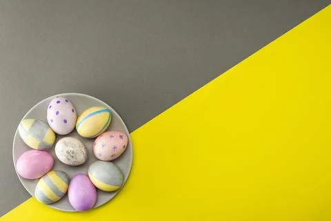 Easter eggs on a gray plate on a gray-yellow background with place for text.  Stock Photos