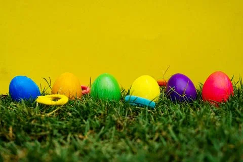 Easter Eggs in Green Grass against Vibrant Yellow Backdrop Stock-Fotos