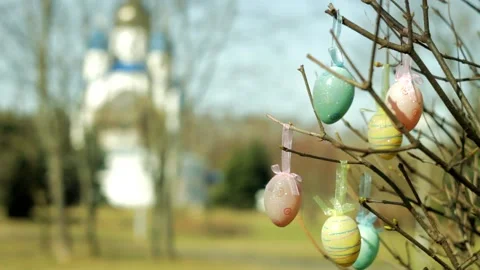 Easter eggs hang on branches against the backdrop of an Orthodox church. Stock Footage 235165602