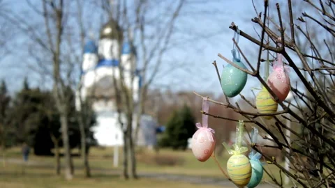 Easter eggs hang on the branches of a tree against the backdrop of a Christian c Stock Footage 234124240