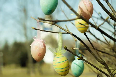 Easter eggs hang on tree branches against the backdrop of the church with domes. Stock Photos