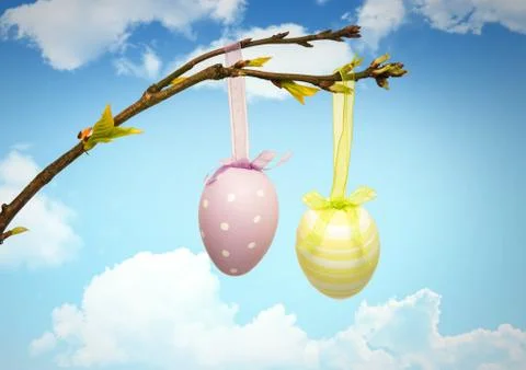 Easter eggs hanging on branch in front of blue sky Stock-Fotos