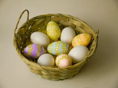Easter eggs in a large basket on a light background. Stock Photos