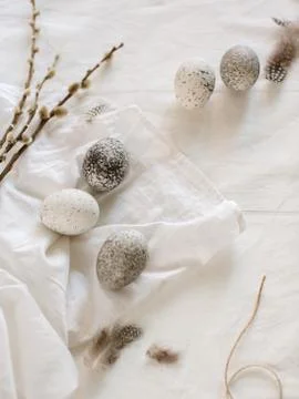 Easter eggs lie on a white tablecloth near the willows Stock Photos