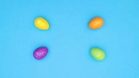 Easter eggs moving from edges to center on blue background - Stop motion Stock Footage 124357972